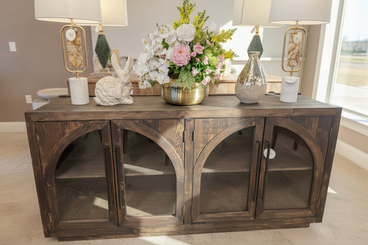 Wooden console table with decorative items including a vase, candles, and a rabbit figurine in a store setting.