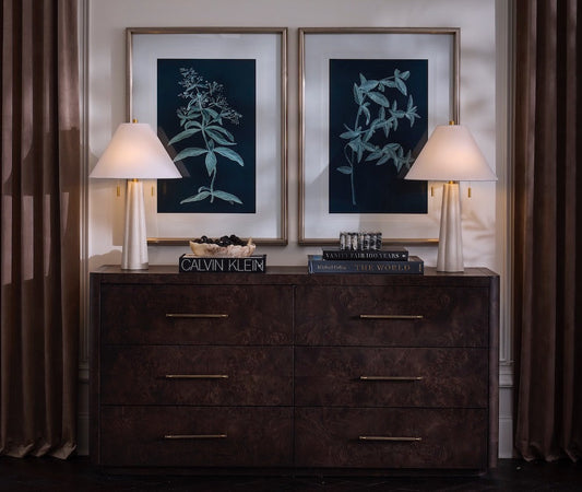 Dark wooden dresser with framed artwork and lamps in a room setting.