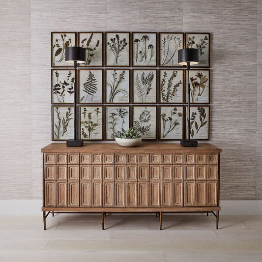 Wooden sideboard with framed botanical prints on a wall.