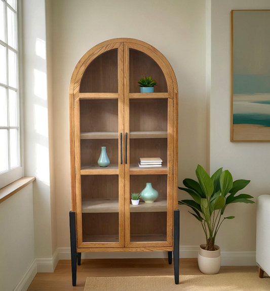 Wooden arched bookshelf in a living room with decor items and a plant.