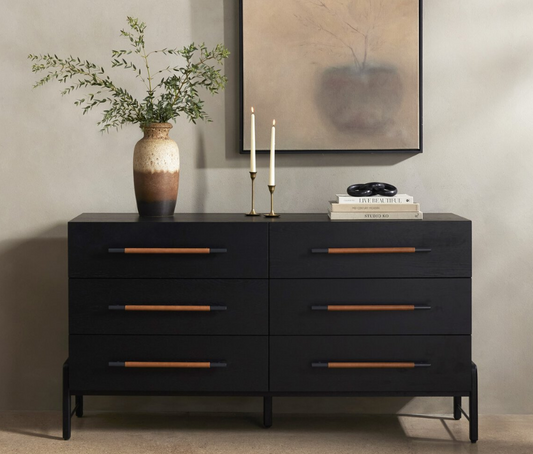 Black dresser with wooden handles in a room setting with decor elements.