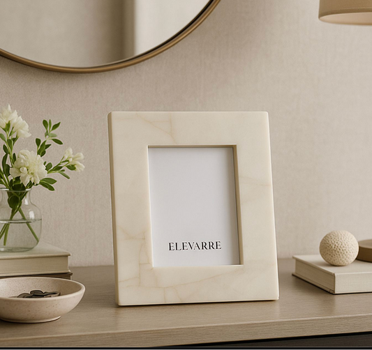 Beige picture frame with 'ELEVARRE' branding on a decorative shelf with a vase, books, and lamp.