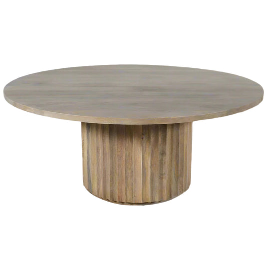 Round light mango wood table with a scalloped base on a white background