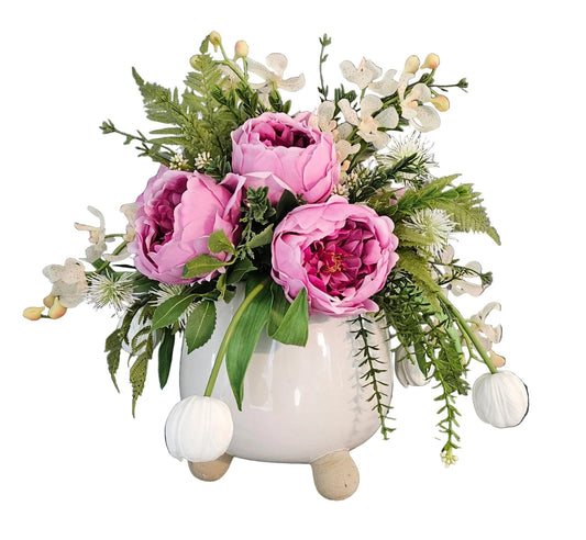 Floral arrangement in a white vase on a wooden surface with a dark gray wall in the background.