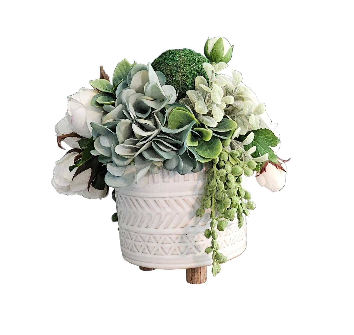 Faux succulent and floral arrangement in a white pot on a wooden surface with a gray wall background.