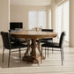 Round wooden dining table with black chairs in a showroom setting