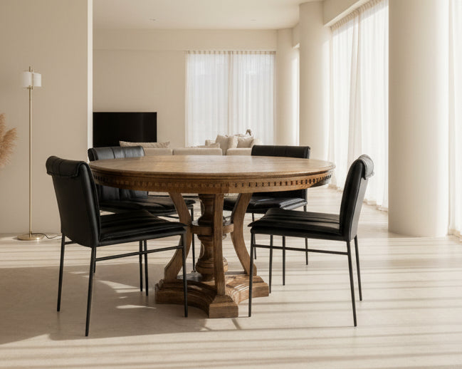 Round wooden dining table with black chairs in a showroom setting