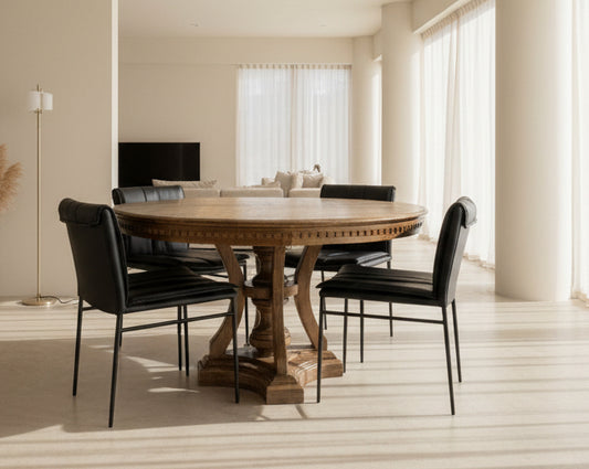 Round wooden dining table with black chairs in a showroom setting