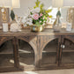 Wooden console table with decorative items including a vase, candles, and a rabbit figurine in a store setting.
