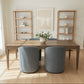 Dining room setup with a wooden table, blue stools, and decorative items in a showroom.