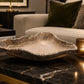 Decorative stone bowl on a marble surface with a candle and books in the background.