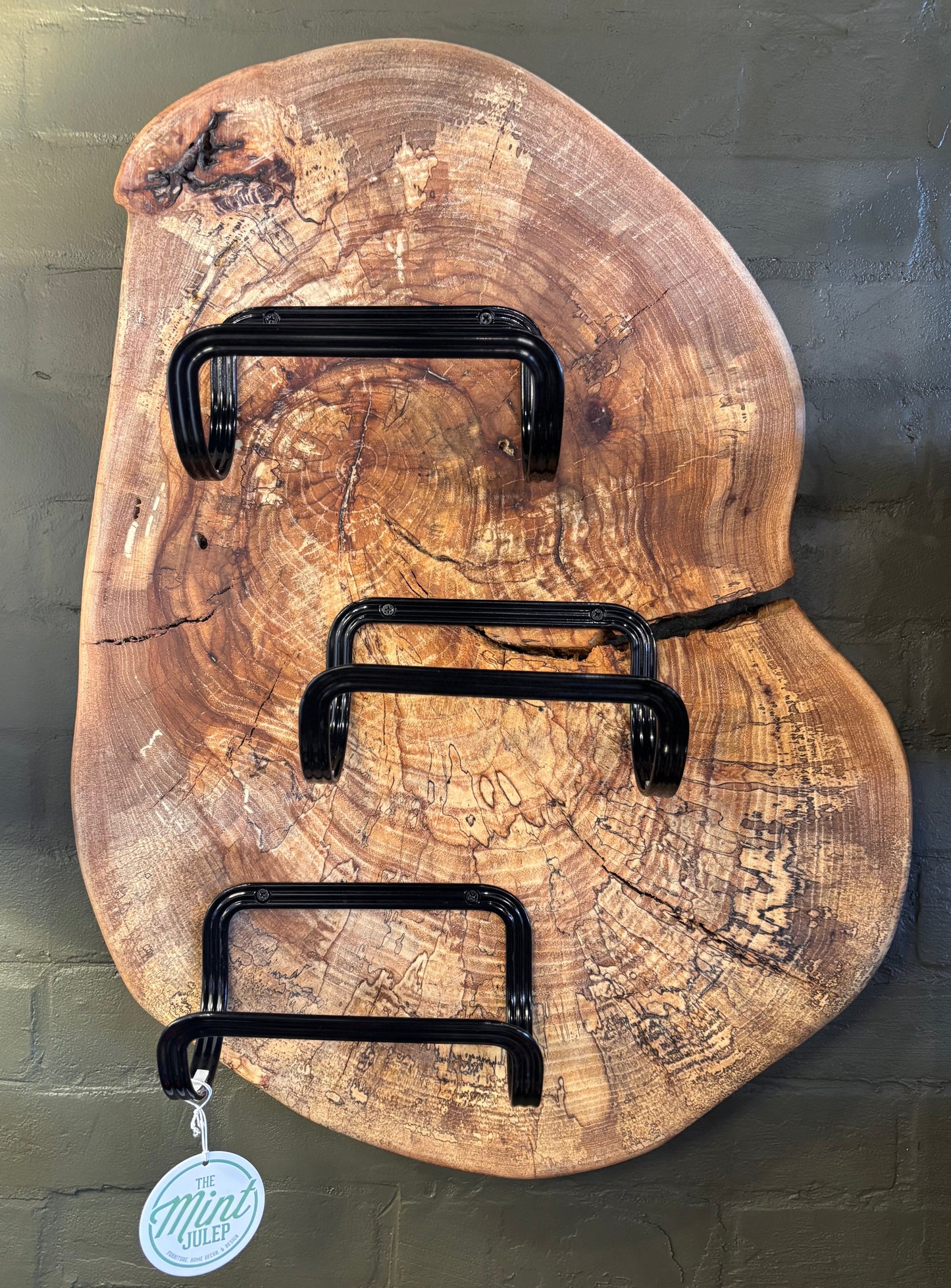 Wooden wall art with black metal hooks on a textured green background