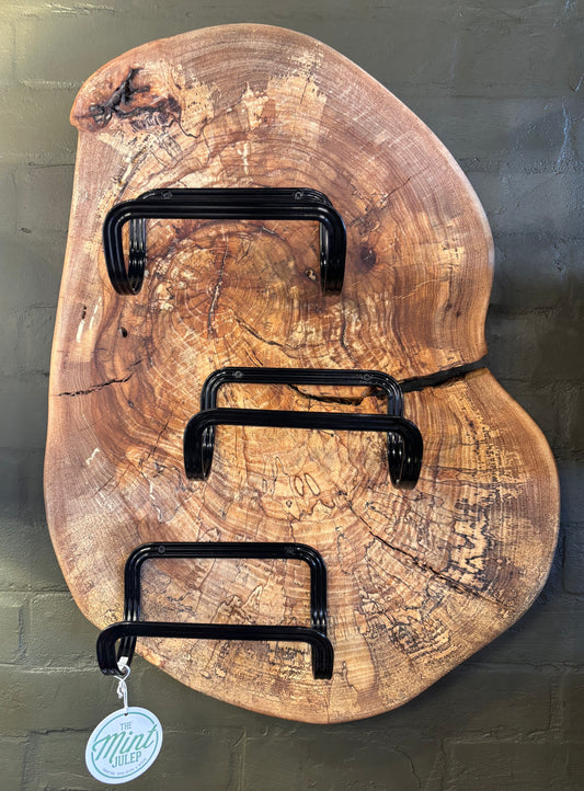 Wooden wall art with black metal hooks on a textured green background