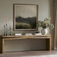 Wooden console table with decorative items against a wall with a framed abstract painting.