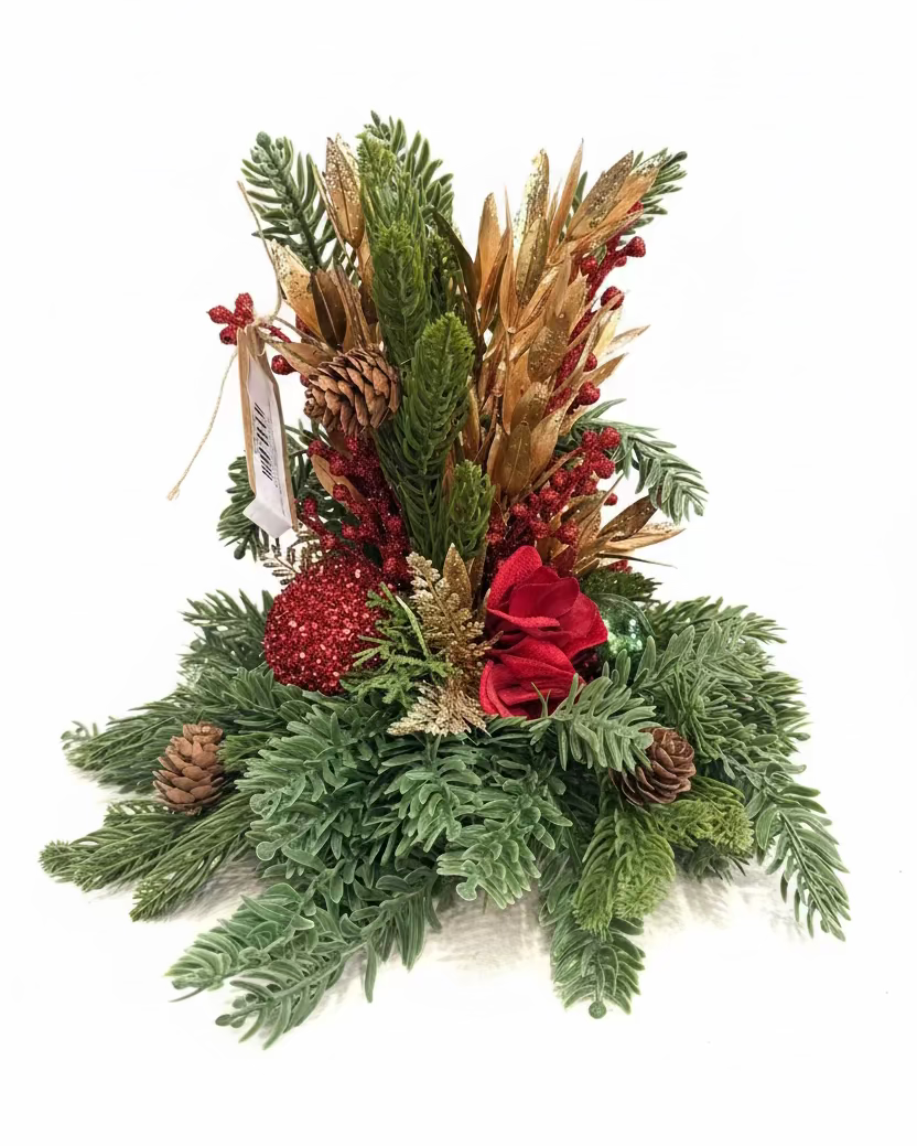 A festive artificial Christmas wreath centerpiece with green pine branches, gold glittery wheat, red berries, pinecones, and a red fabric rose, displayed on a wooden table in a store setting.