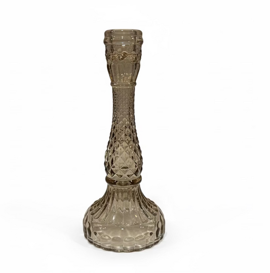 Decorative glass candle holder on a white surface with a blurred background