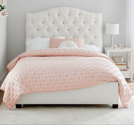 Bedroom with a tufted headboard and pink bedding