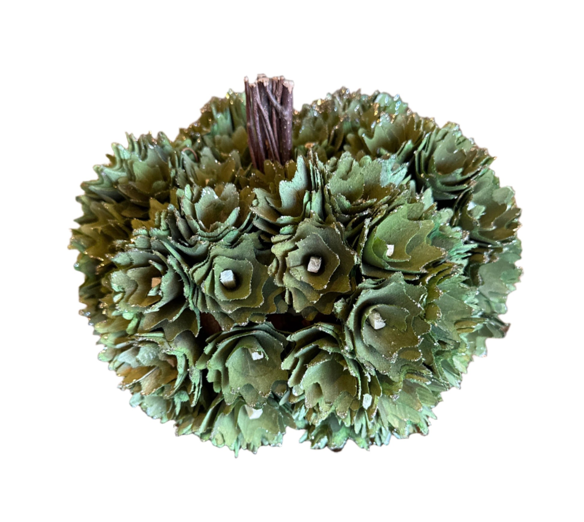 Decorative green pine cone ball on a wooden surface with a white textured background