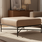Beige ottoman with black metal frame on a white background