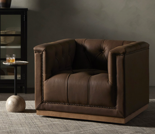 Brown leather armchair in a room with a dark wall and small round table.
