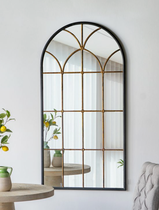 Decorative mirror with a grid pattern in a room with a table and chair.