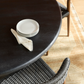 Round black table with white plates and a napkin on a wooden floor.