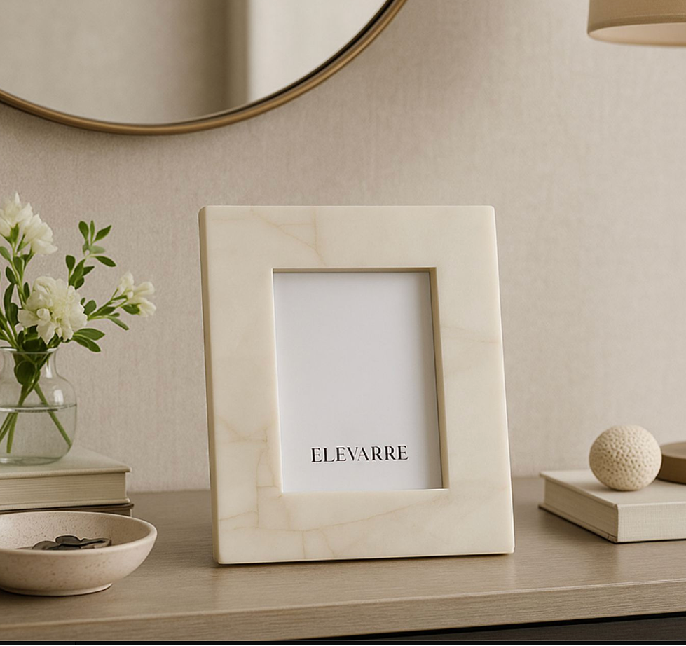 Beige picture frame with 'ELEVARRE' branding on a decorative shelf with a vase, books, and lamp.