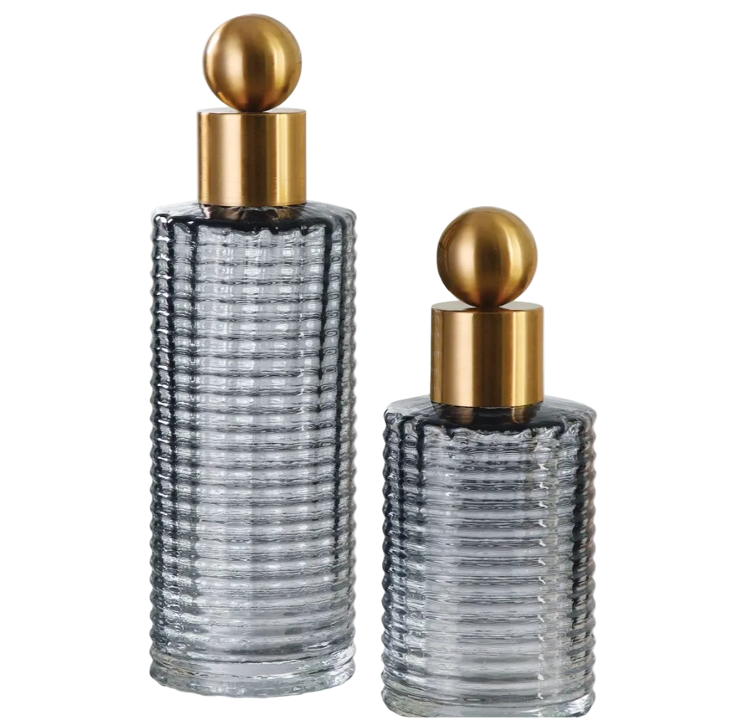 Two glass perfume bottles with gold caps on a white background