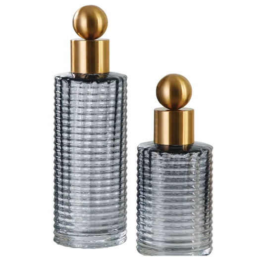 Two glass perfume bottles with gold caps on a white background