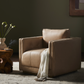 Beige armchair in a dimly lit room with a side table and plant.