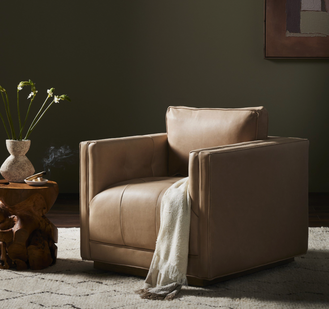 Beige armchair in a dimly lit room with a side table and plant.