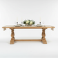 Wooden dining table with decorative legs in a studio setting.