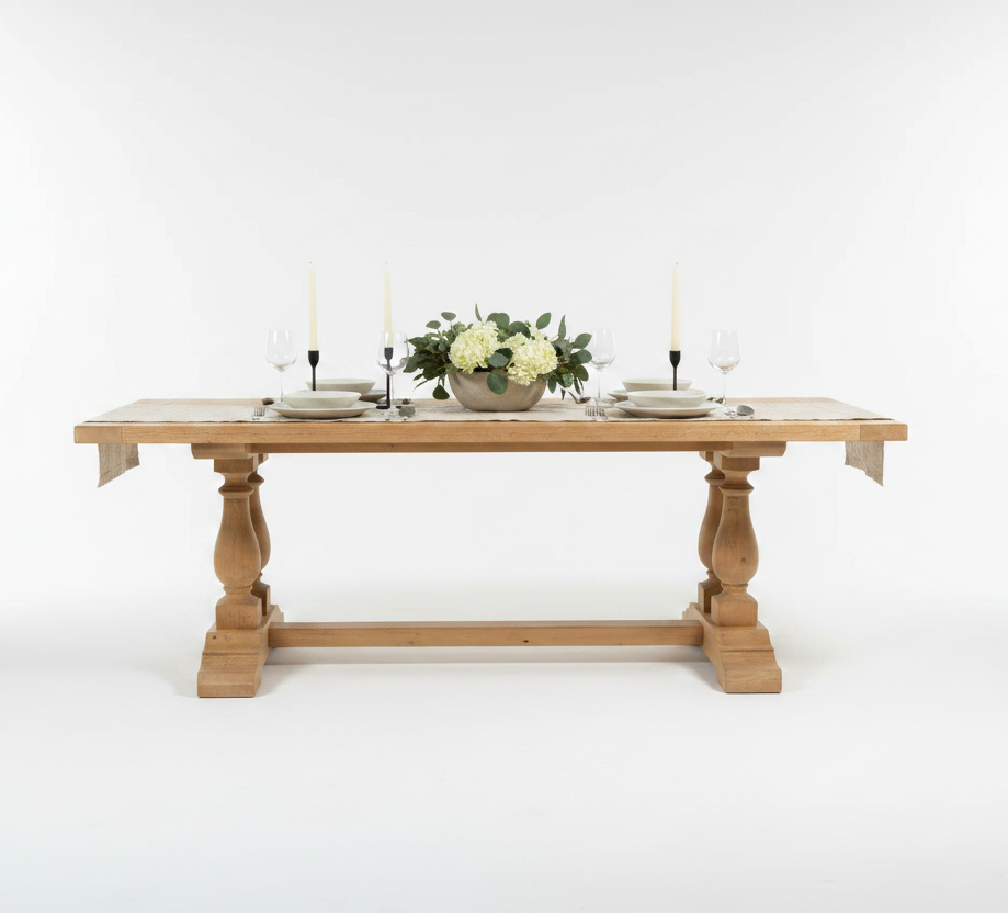 Wooden dining table with decorative legs in a studio setting.