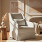 Beige armchair in a room with abstract art on the wall and a small table with decor items.