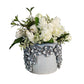 Decorative pot with white flowers on a wooden surface against a white background.