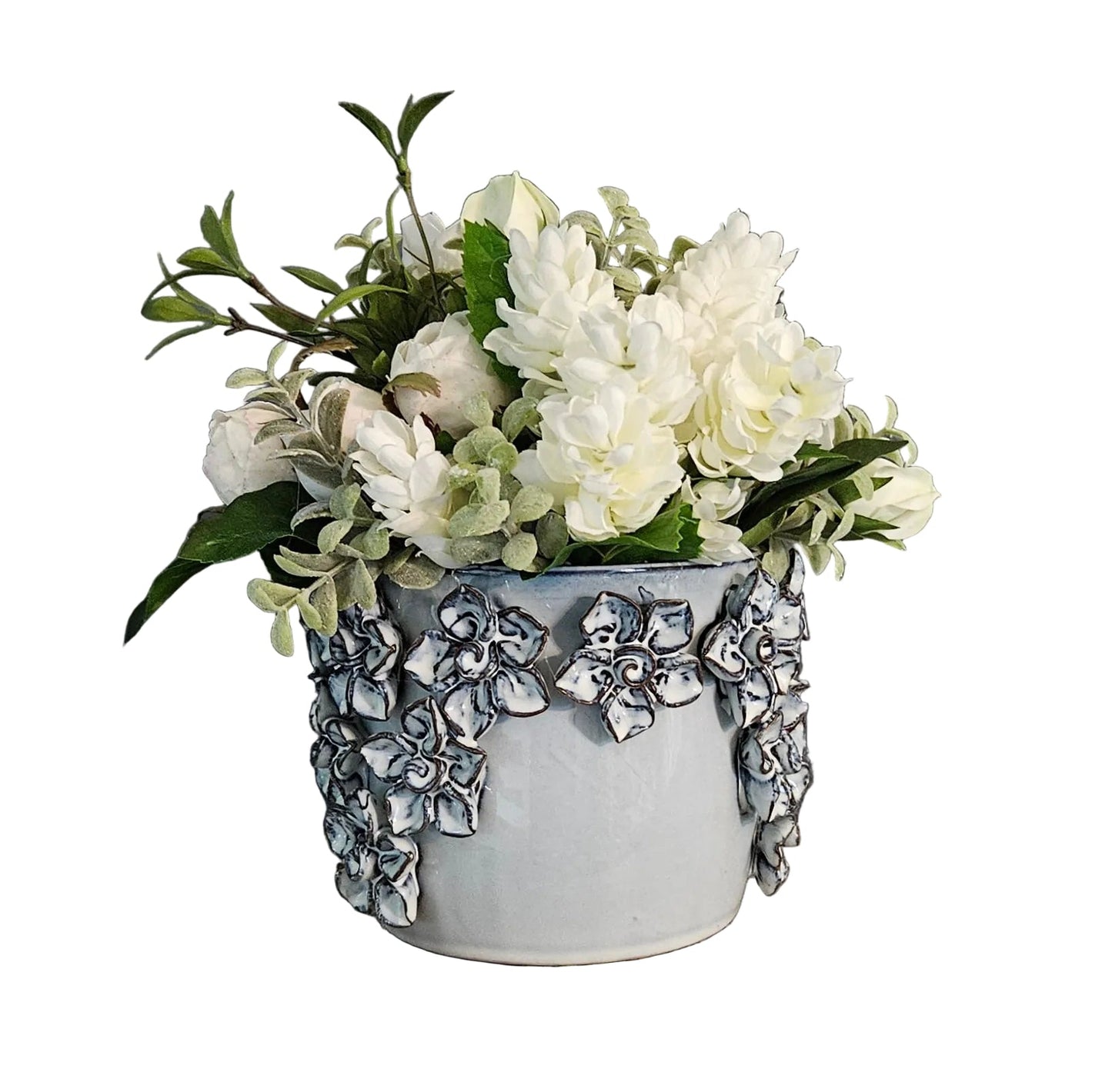 Decorative pot with white flowers on a wooden surface against a white background.