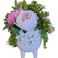 Floral arrangement in a decorative white vase on a wooden surface