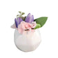 Small white vase with pink and purple flowers on a white background