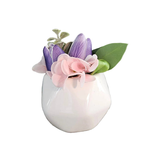 Small white vase with pink and purple flowers on a white background
