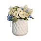 White textured vase with a bouquet of flowers on a white wall.