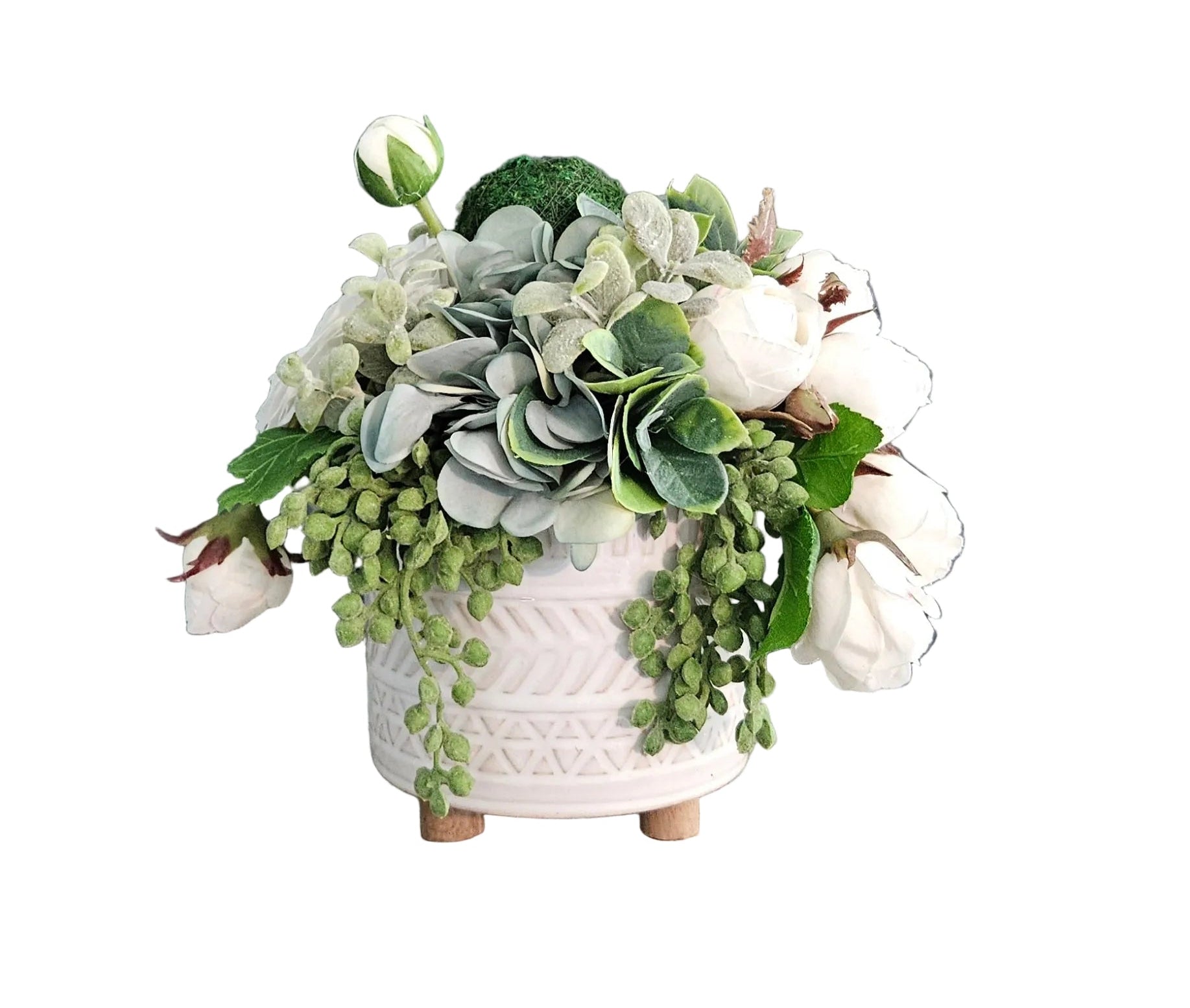 Floral arrangement in a white pot on a wooden surface with a gray wall background