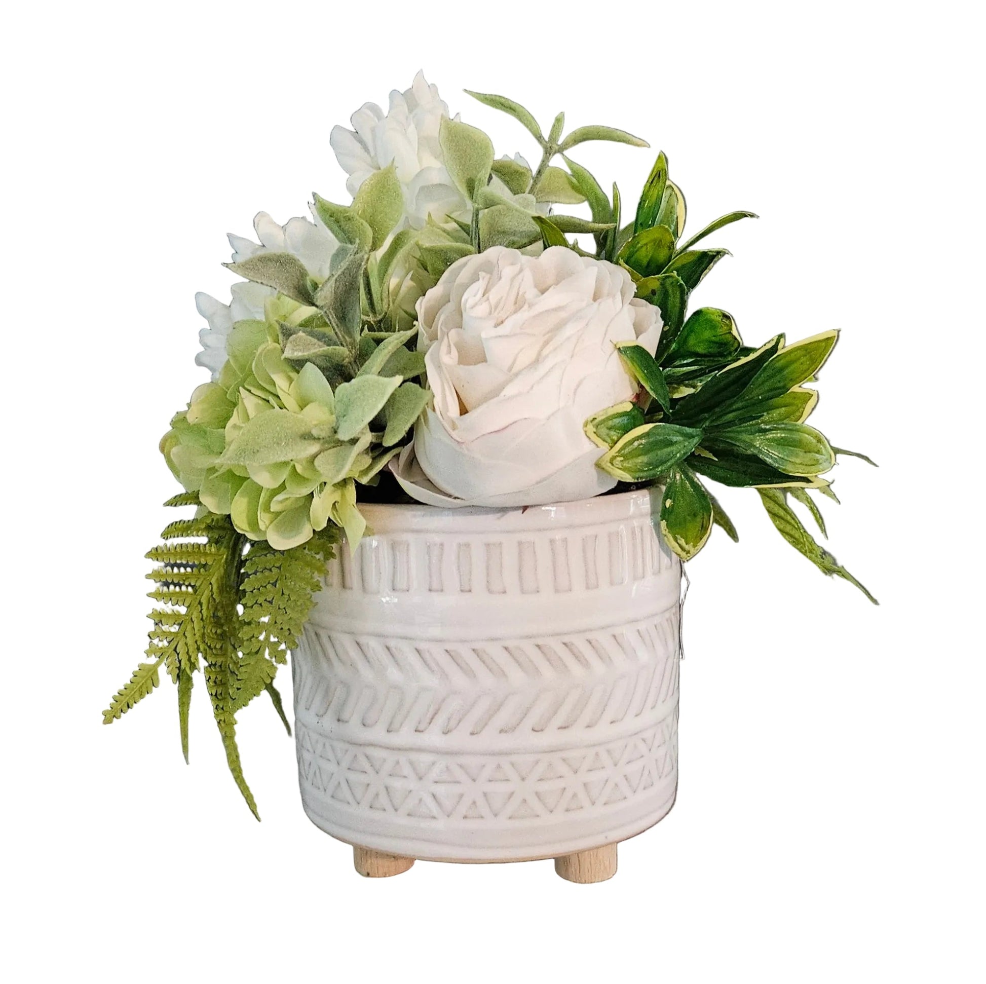White textured pot with artificial greenery and white flowers on a wooden surface against a dark background