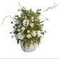 Floral arrangement in a white vase on a wooden surface with decorative text in the background.