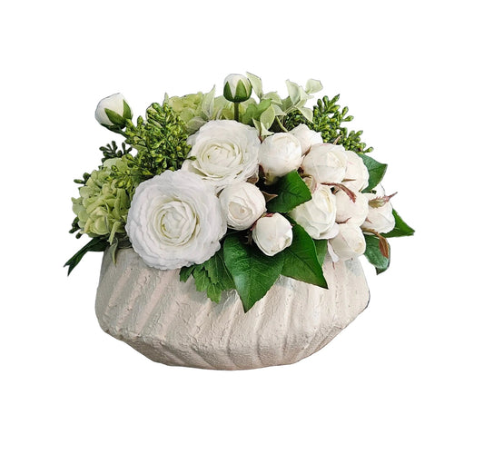 Floral arrangement in a textured vase on a wooden surface with a gray wall background