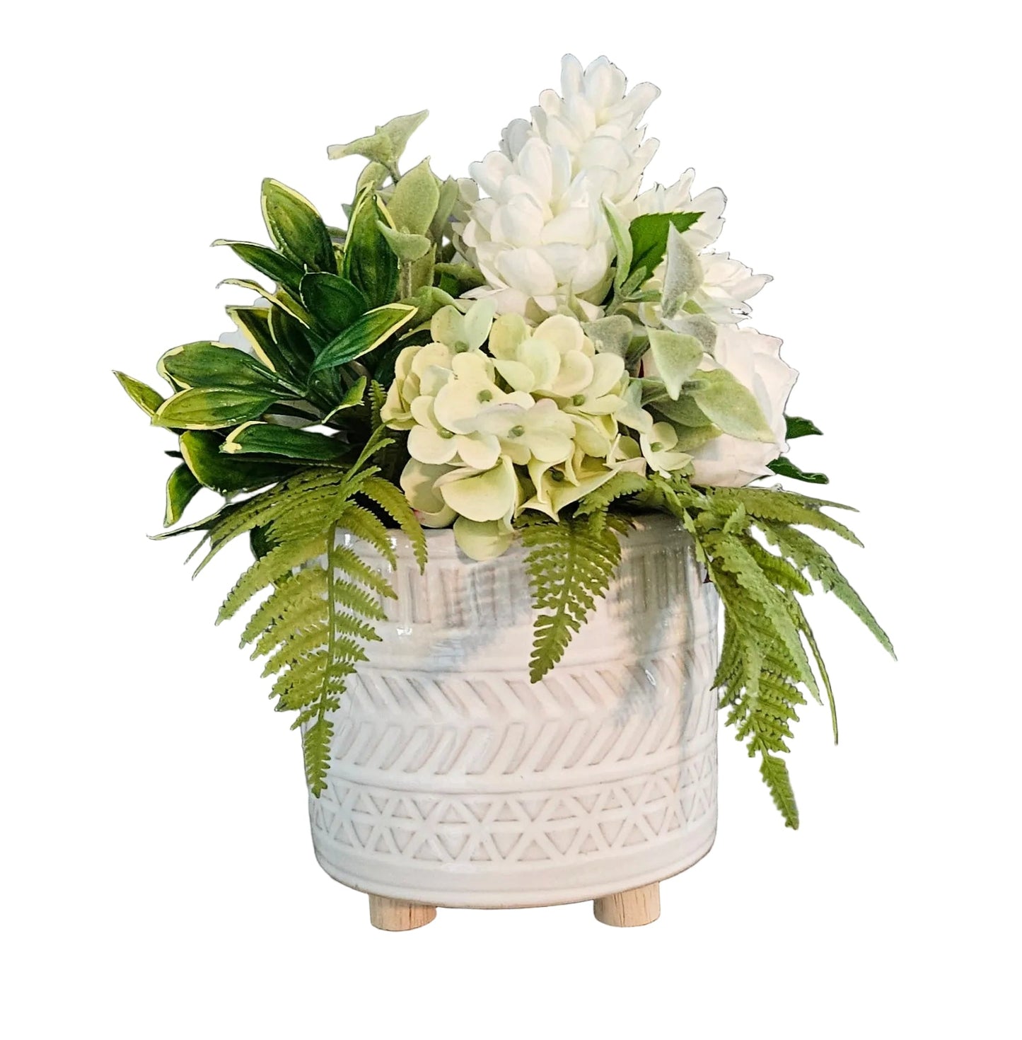 White textured vase with green and white flowers on a wooden surface against a dark wall