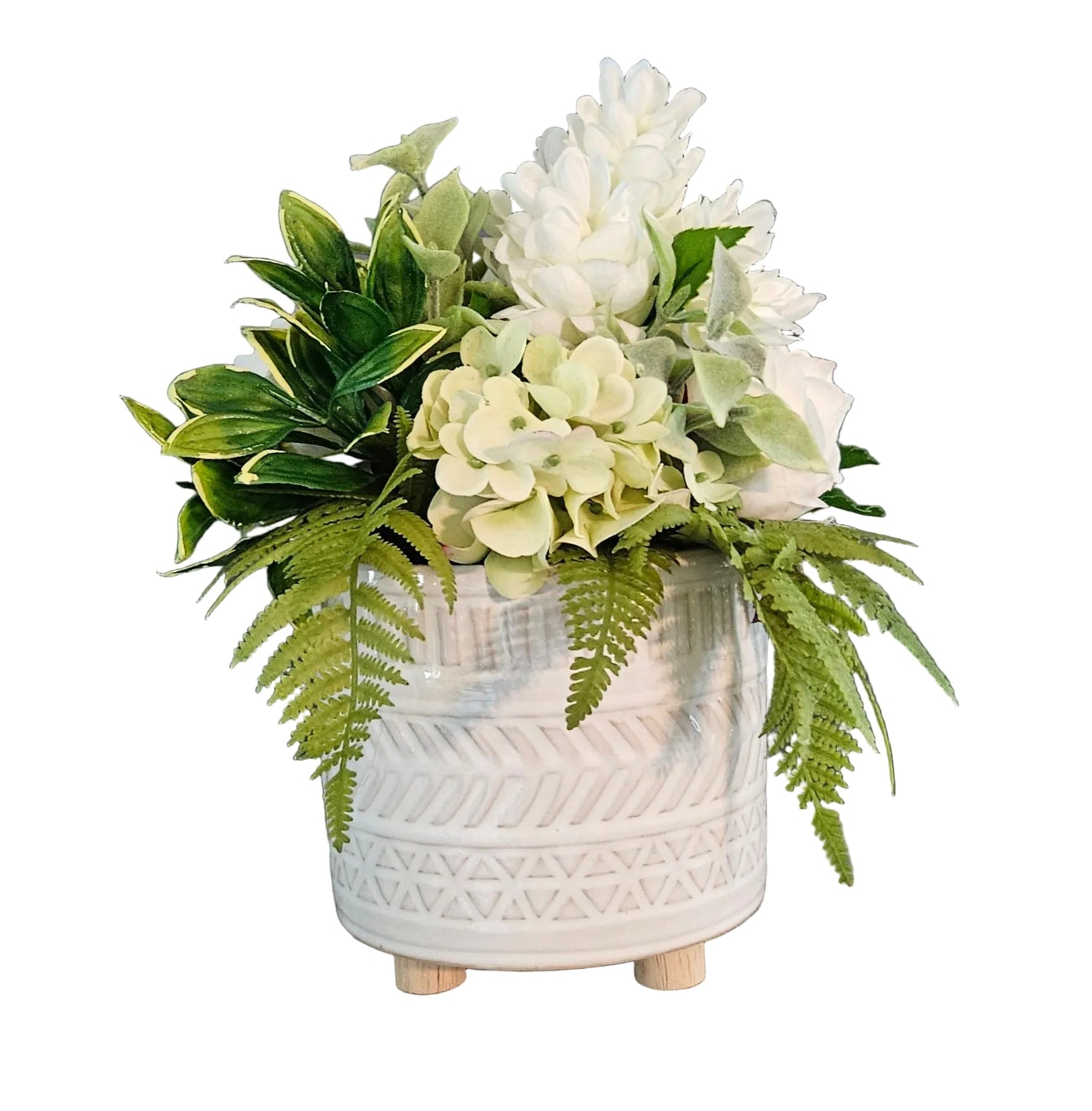 White textured vase with green and white flowers on a wooden surface against a dark wall