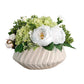 Decorative flower arrangement in a textured vase on a rustic wooden surface with a gray wall background.