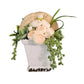 Floral arrangement in a white vase on a rustic wooden surface on a white wall
