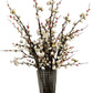 Artificial floral arrangement with white flowers and red berries in a clear glass vase on a white background