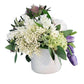 Floral arrangement in a white vase on a wooden surface with a gray wall background